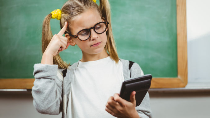 Cute pupil calculating with calculator in a classroom in school